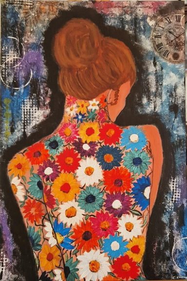 A woman with a flower-covered back, showcasing vibrant blooms against a dark background.