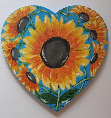 Heart-shaped decoration featuring bright sunflowers on a blue background.